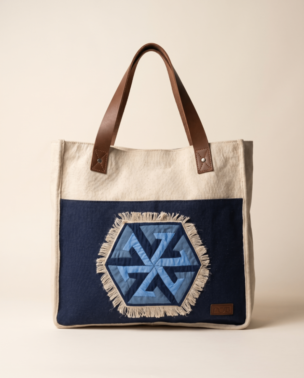 Canvas tote with blue khayamiya-inspired front panel and brown leather handles.
