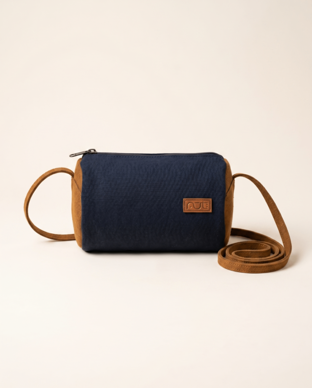 Blue cylindrical crossbody bag with tan leather sides and strap.