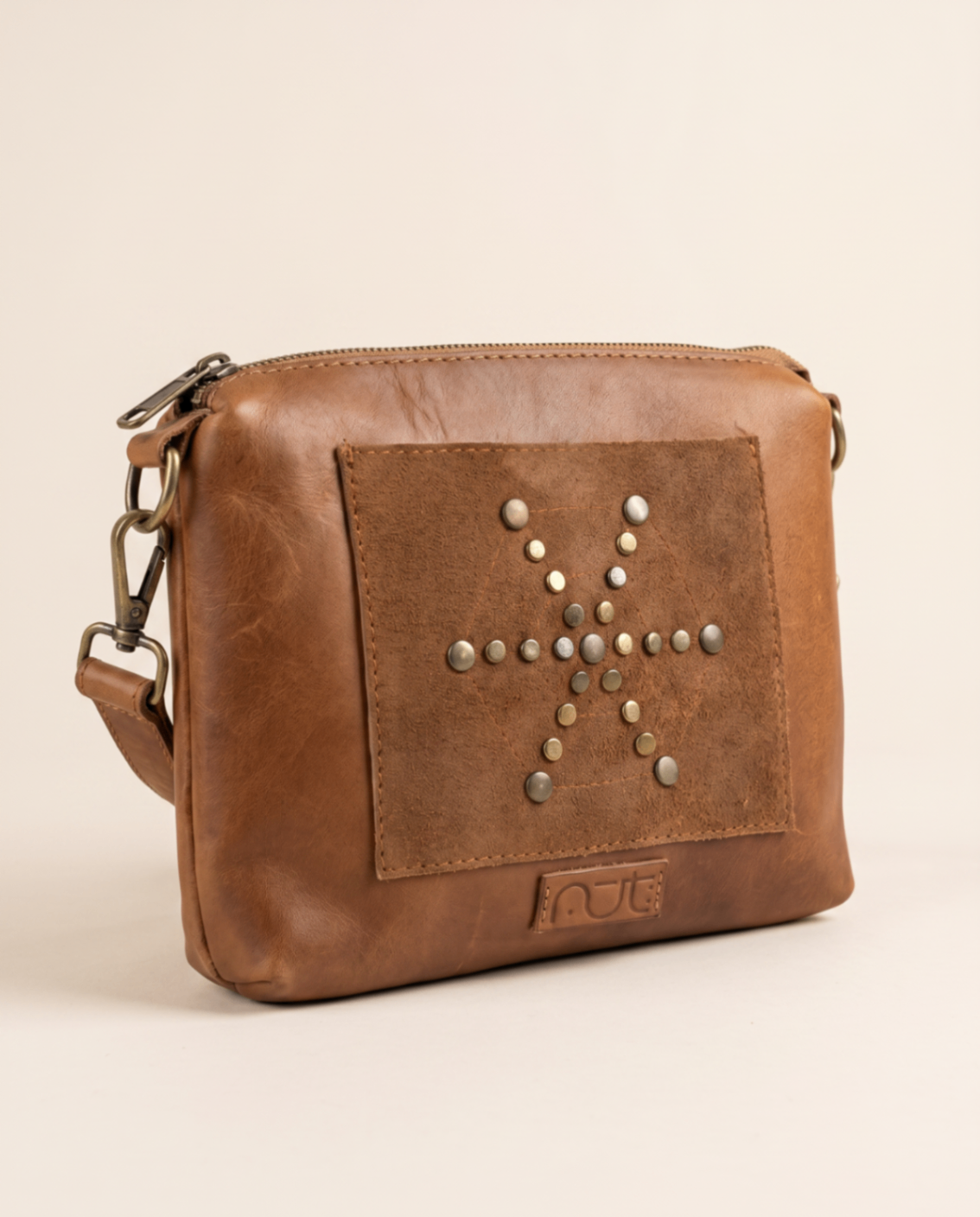 Camel leather clutch with a studded motif panel on the front.